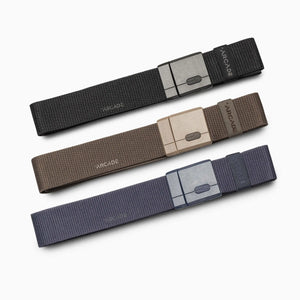 Three Arcade Belts Mag Kit fabric belts in black, brown, and navy are laid out flat in parallel rows, each featuring a rectangular SwiftLock buckle and “ARCADE” printed near the buckle.