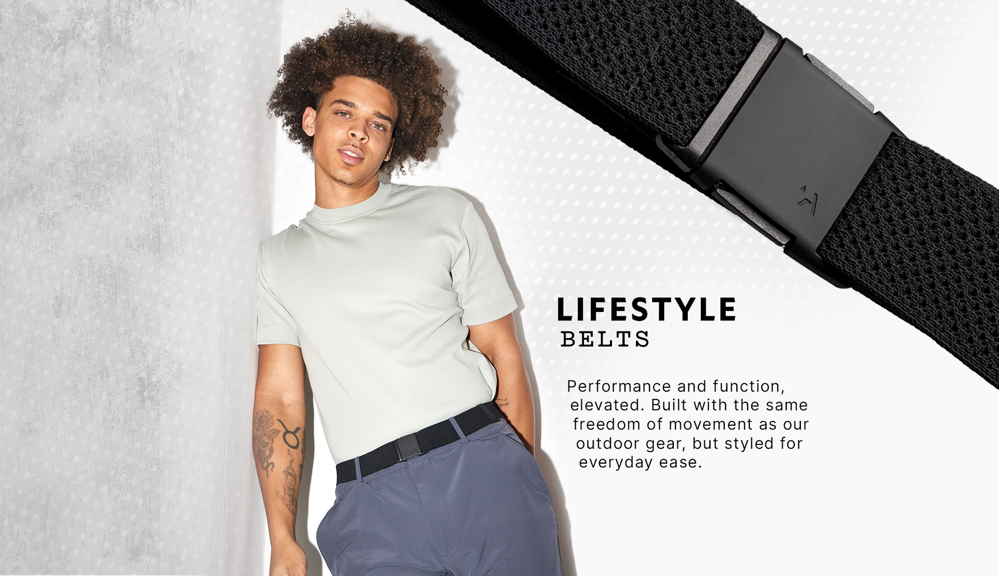 A person with curly hair wears a light grey shirt, blue pants, and an Elastic Stretch Belt. To the right, a close-up highlights the textured black belt and buckle. Text describes this stylish travel belt as both functional and comfortable for everyday use.