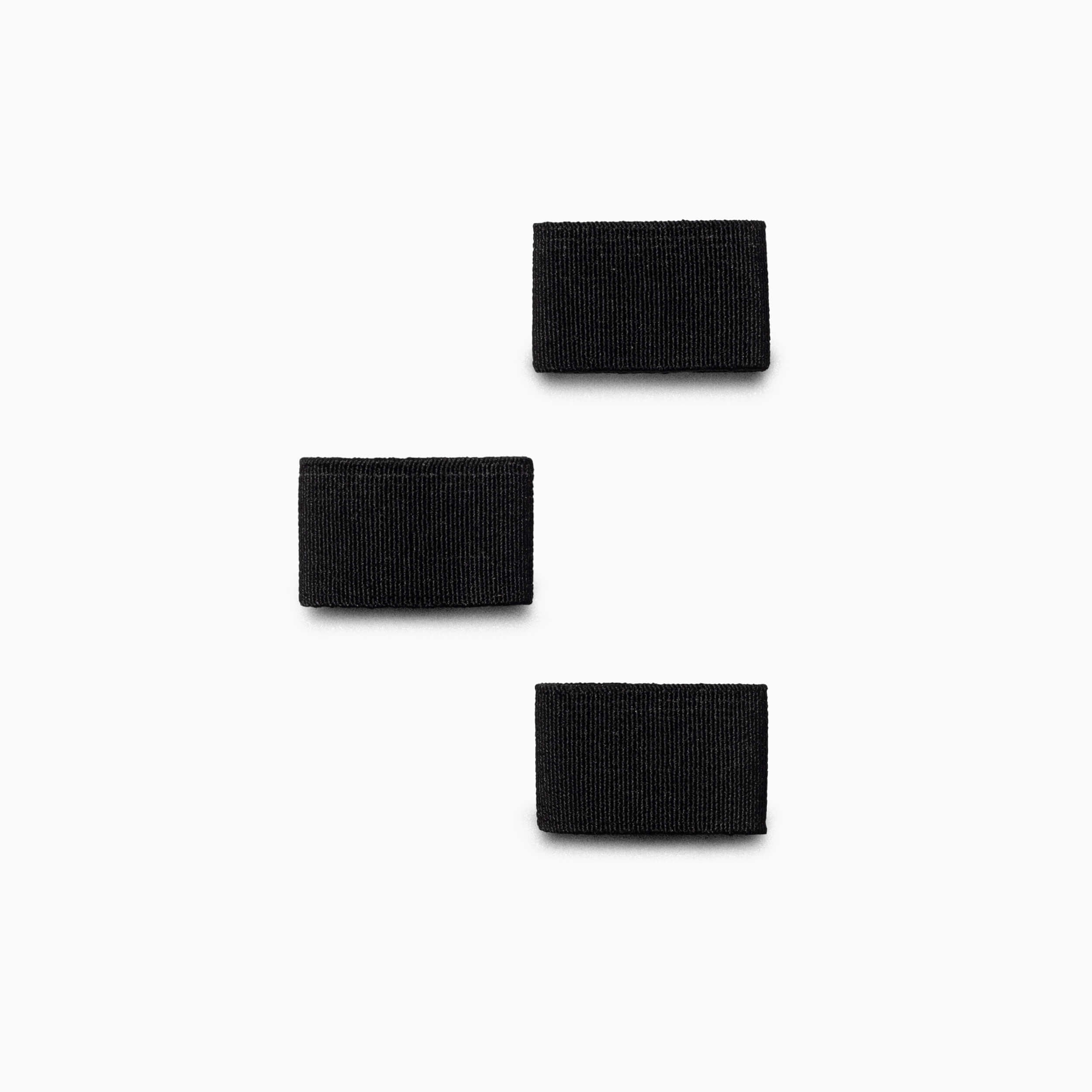 Three black rectangular Hardware Belt Loopkeepers by Arcade Belts, resembling stretch webbing, are arranged vertically on a white background, with the middle loopkeeper shifted to the left.
