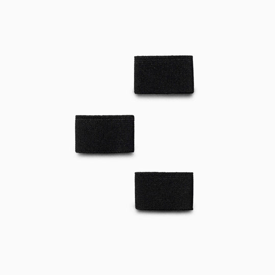 Three black rectangular Hardware Belt Loopkeepers by Arcade Belts, resembling stretch webbing, are arranged vertically on a white background, with the middle loopkeeper shifted to the left.
