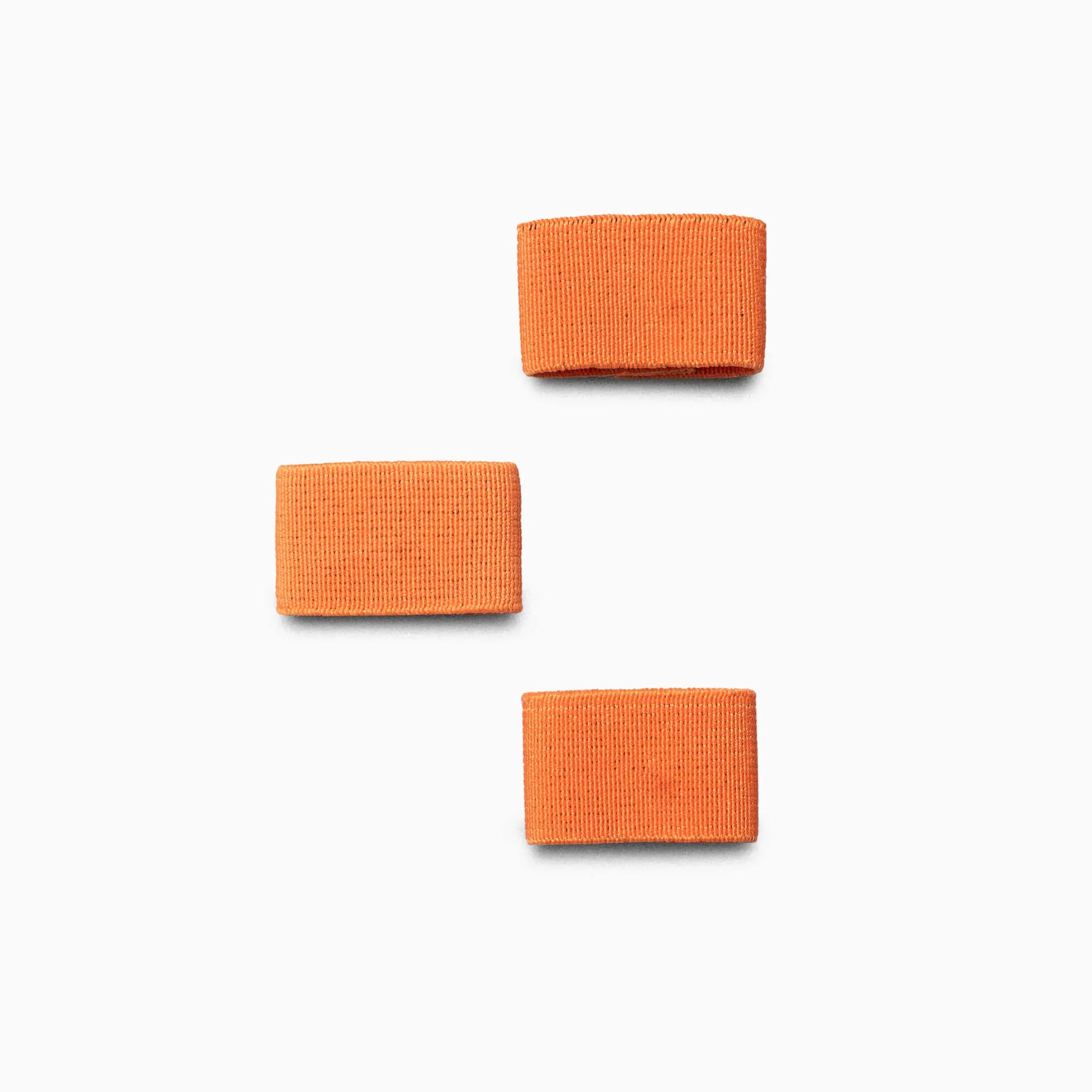 Three rectangular orange Arcade Belts Hardware Belt Loopkeepers are arranged on a white background in a triangular pattern, with two on the left and one on the upper right.