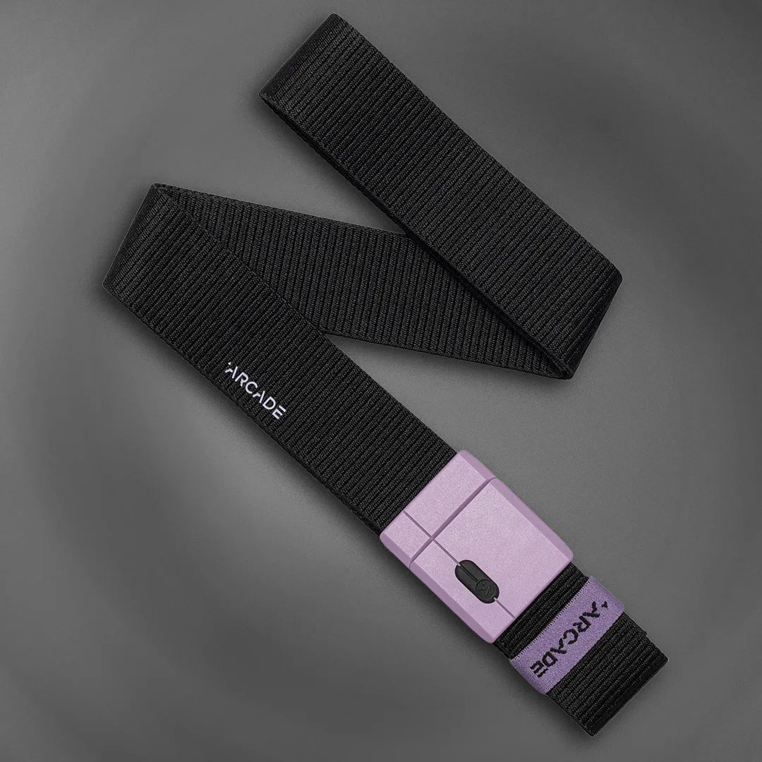 A black fabric belt with a purple rectangular buckle, featuring the ARCADE logo printed in white on both the belt and the buckle, laid out on a dark gray background.