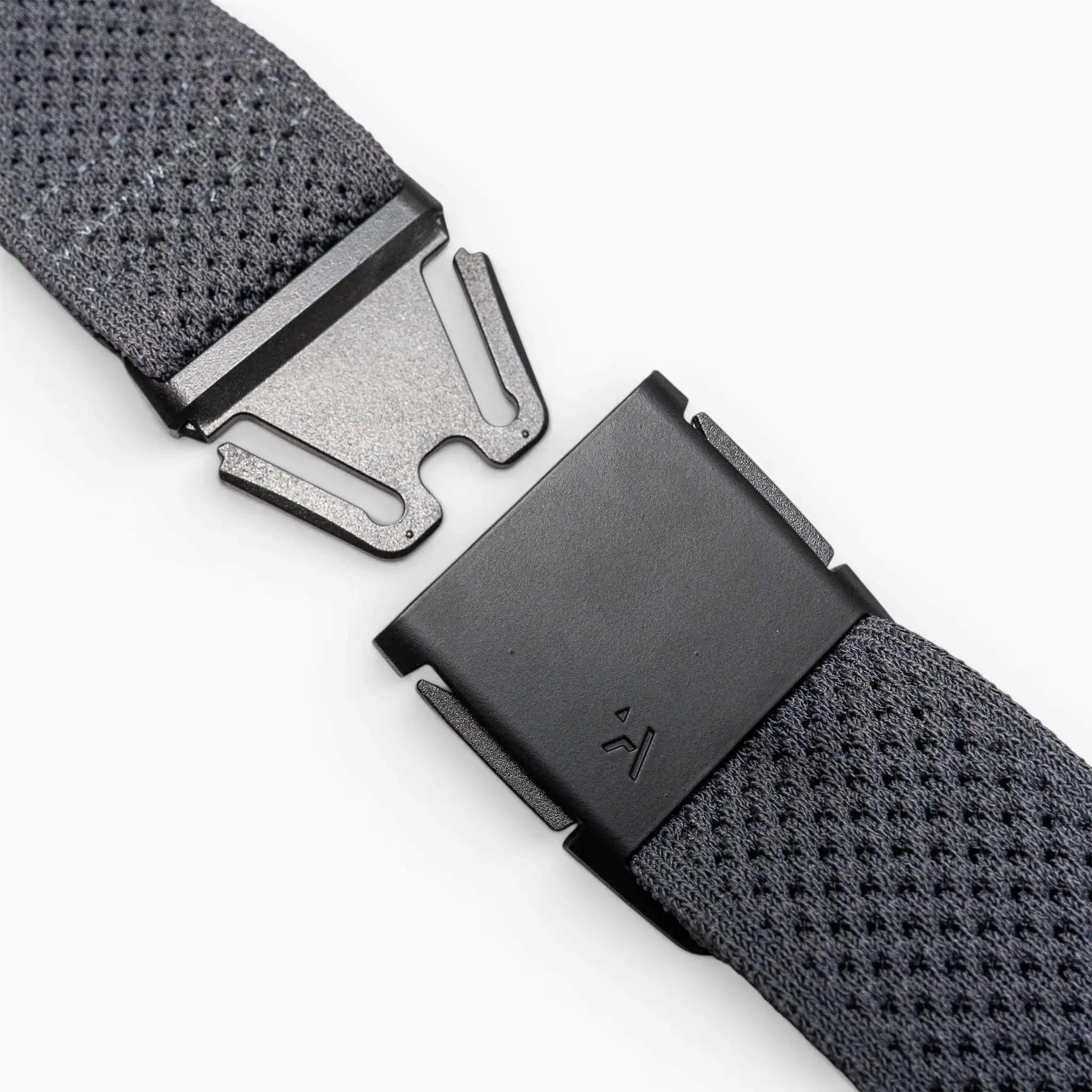 Close-up of the Arcade Belts Momentums black metal buckle on a textured gray strap, featuring a partially open, geometric modern design inspired by low-profile belt styles, set against a plain light background.