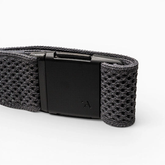 A close-up of the Arcade Belts Momentum strap shows its black textured fabric and rectangular black plastic buckle on a light grey background, highlighting its signature low-profile design.