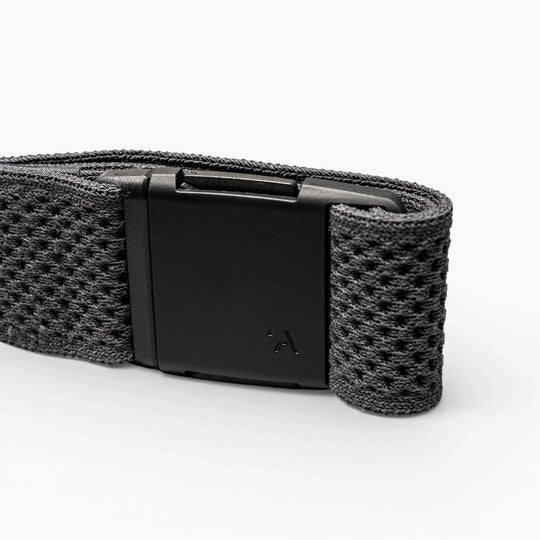 A close-up of the Arcade Belts Momentum strap shows its black textured fabric and rectangular black plastic buckle on a light grey background, highlighting its signature low-profile design.