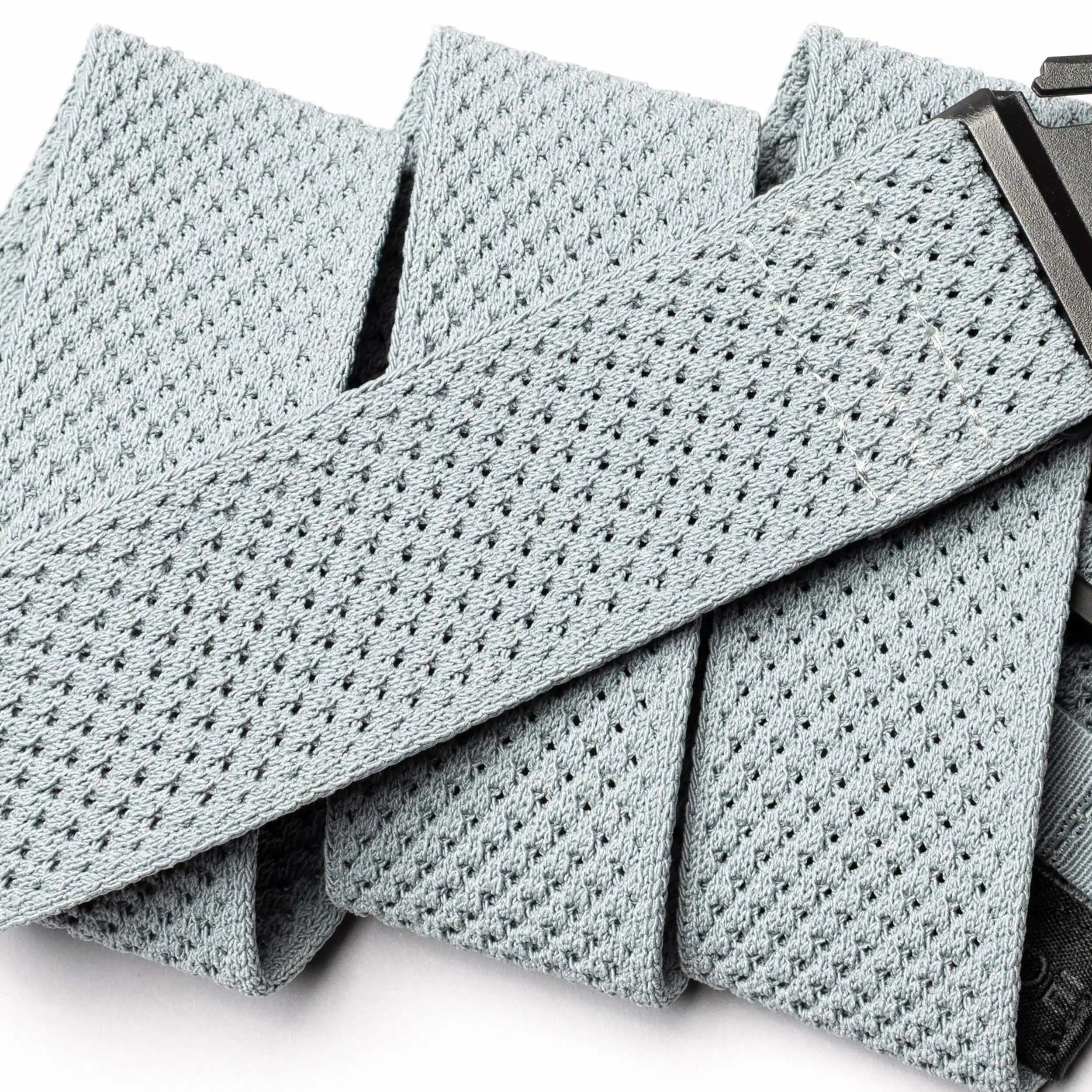 A close-up of the light grey Arcade Belts Momentum, featuring a rectangular black plastic buckle and highlighting the textured, perforated material of this travel belt.