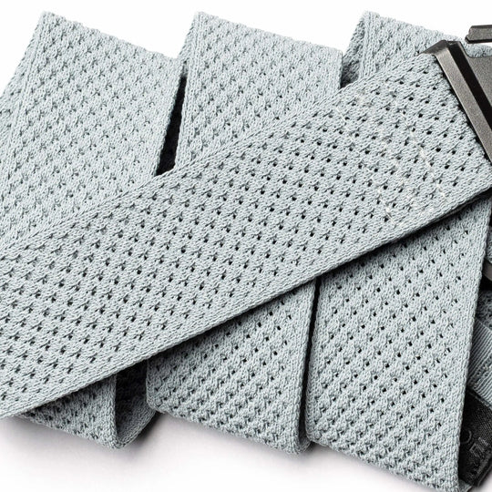 A close-up of the light grey Arcade Belts Momentum, featuring a rectangular black plastic buckle and highlighting the textured, perforated material of this travel belt.