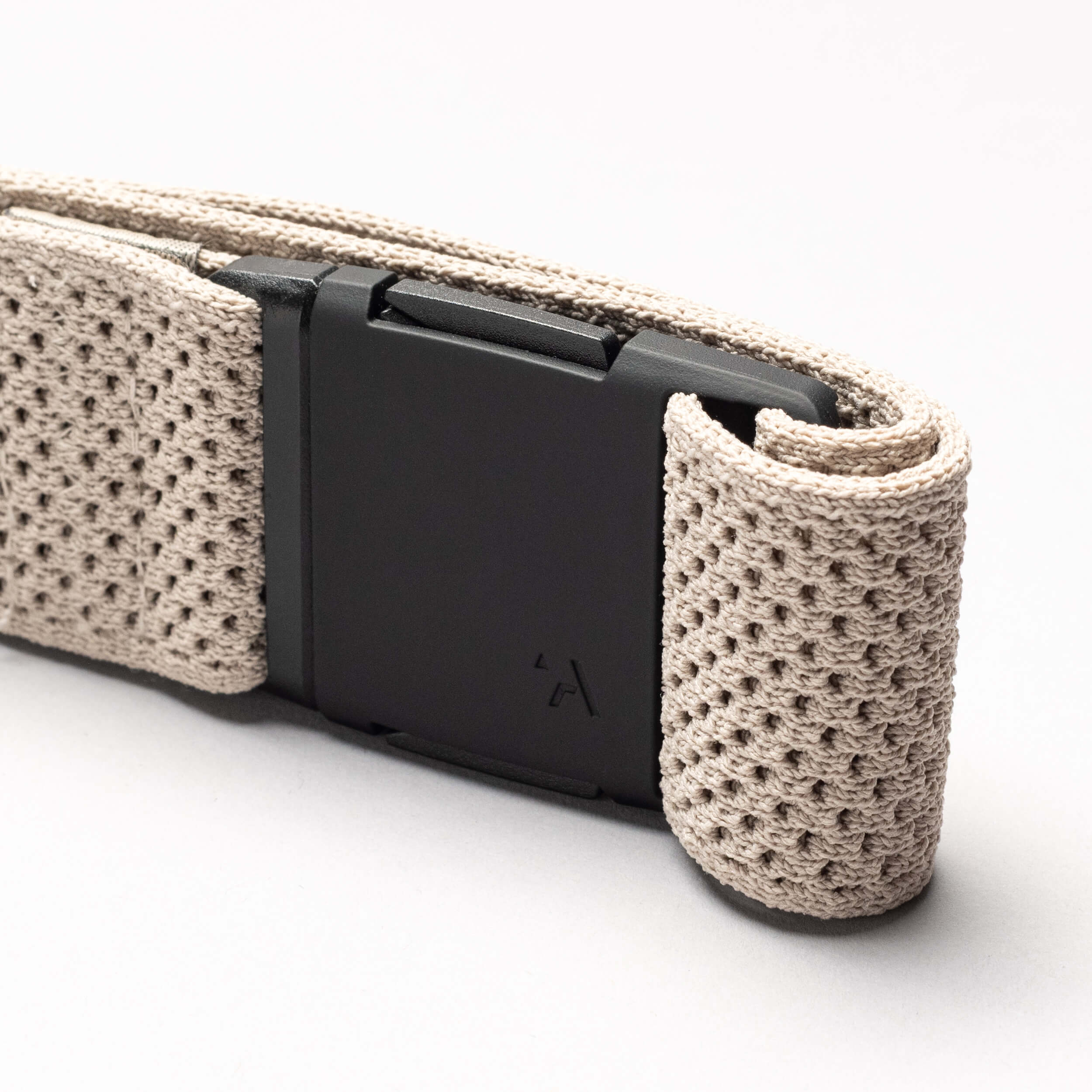 A close-up of the Arcade Belts Momentum: a beige, textured woven low profile belt with a matte black rectangular buckle, set against a plain light background.