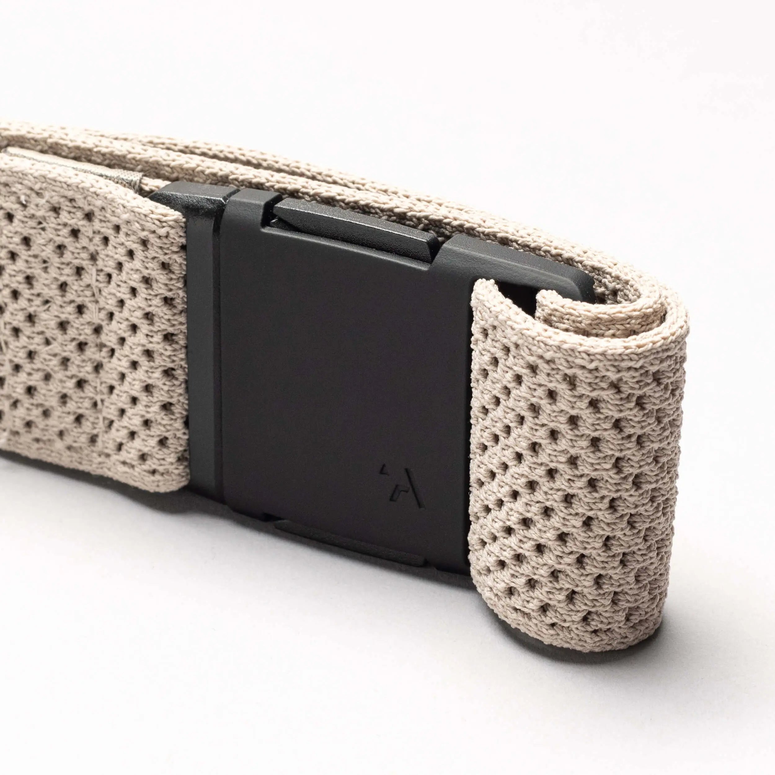 A close-up of the Arcade Belts Momentum: a beige, textured woven low profile belt with a matte black rectangular buckle, set against a plain light background.