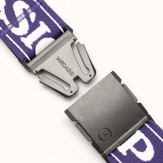 A close-up of the Arcade Belts Mothership Classic, a black plastic buckle engraved with ARCADE on a purple and white patterned belt, designed to honor the High Fives Foundation, shown partially unclasped on a white background.