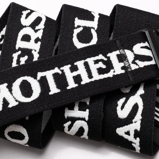 A close-up of the Arcade Belts Mothership Classic, a black stretch webbing low-profile belt with bold white MOTHERS text and overlapping letters, finished with a sleek black plastic buckle.