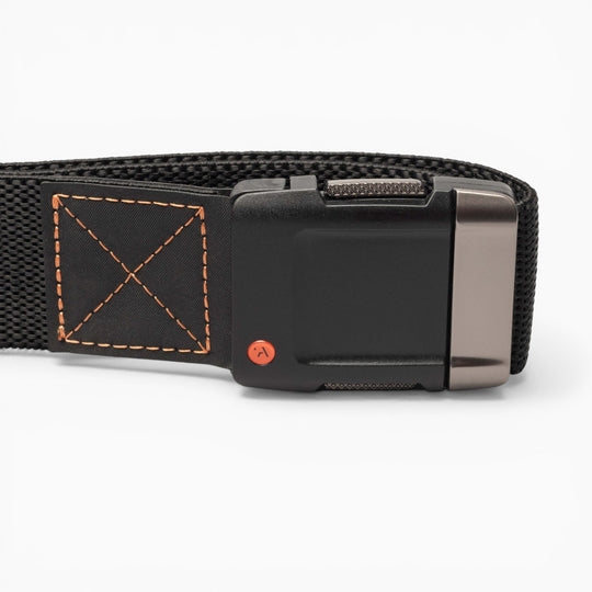 Close-up of the Arcade Belts Motion, a black woven fabric belt featuring a rectangular black buckle with a metallic accent and orange stitching on the belt loop, designed for comfort and modern style, set against a white background.