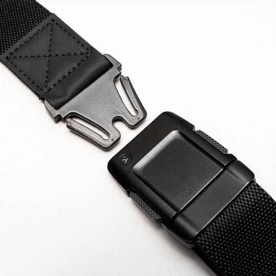 Close-up of the Arcade Belts Motion, a black tactical belt with a metal quick-release buckle, showcasing its modern style and comfortable fit, partially unfastened on a white surface.