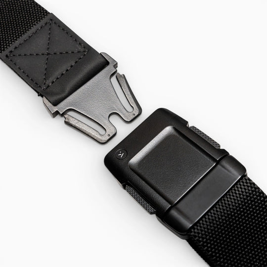 Close-up of the Arcade Belts Motion, a black tactical belt with a metal quick-release buckle, showcasing its modern style and comfortable fit, partially unfastened on a white surface.