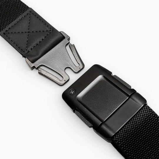 Close-up of the Arcade Belts Motion, a black tactical belt with a metal quick-release buckle, showcasing its modern style and comfortable fit, partially unfastened on a white surface.