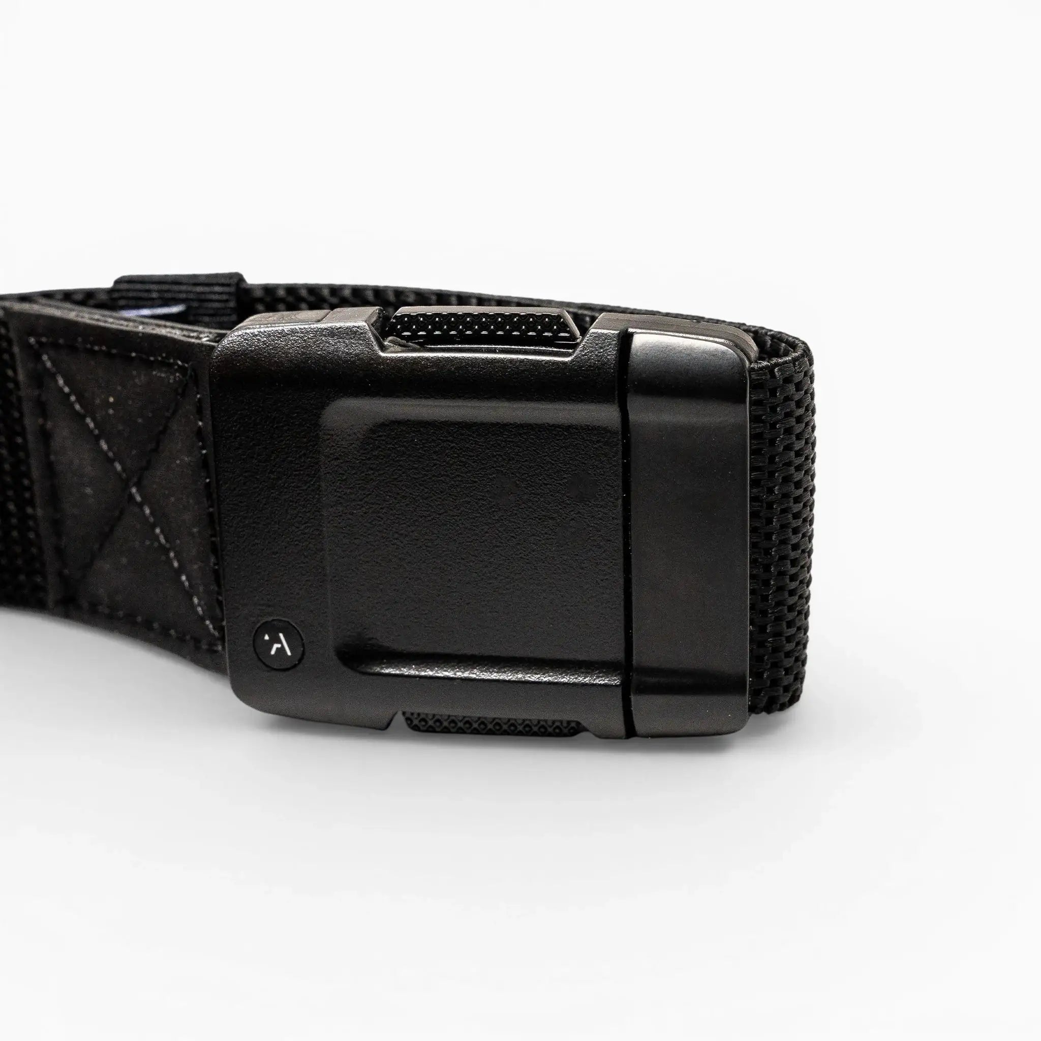 Close-up of the Arcade Belts Motion: a black fabric strap with a rectangular, textured plastic buckle on a white background. The buckle has a small round button with a curved arrow for secure fastening and easy adjustment—perfect for travel.