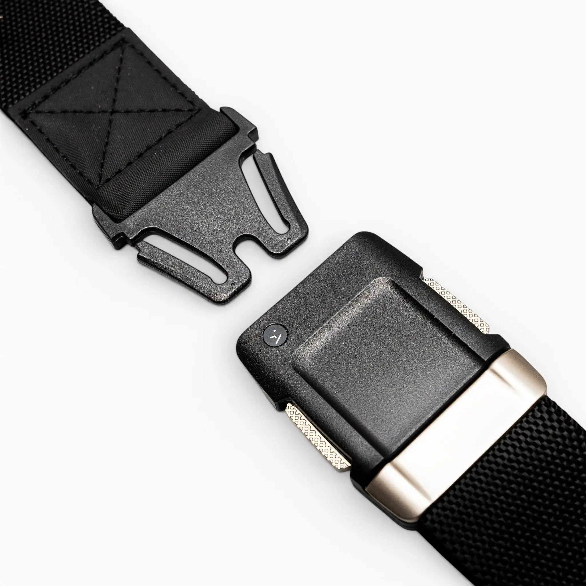 Close-up of the Arcade Belts Motion: a black nylon belt with a sturdy, quick-release black plastic buckle featuring metallic accents. The partially unfastened buckle highlights its clean, modern design against a light gray background.