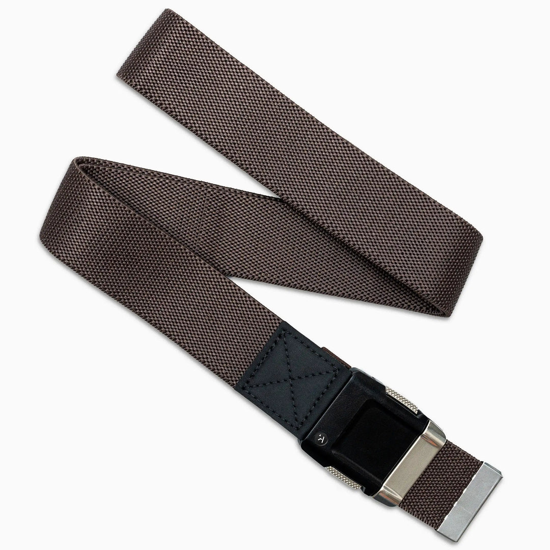 The Arcade Belts Motion is a brown stretch webbing belt with a textured pattern, black leather accent, and silver buckle. Shown loosely overlapped on a white background, this low-profile belt blends style and comfort.