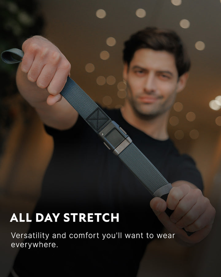 A man in a black shirt stretches a gray Low Profile Belt with a plastic buckle towards the camera. Text reads: ALL DAY STRETCH. Versatility and comfort from Arcade Belts you’ll want to wear everywhere.