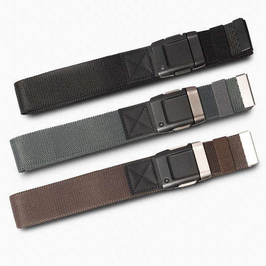 Three Arcade Belts Motion Kit travel belts with sturdy metal buckles are arranged horizontally on a white background, shown in black, gray with a black stripe, and brown with a darker brown stripe.