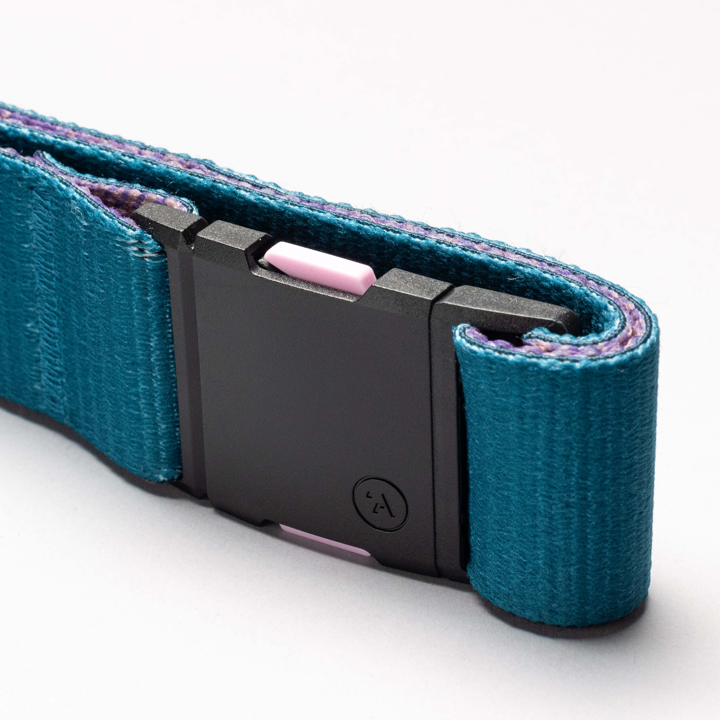 A close-up of the Arcade Belts National Geographic teal belt, featuring a black rectangular plastic buckle and a small pink accent, coiled on a plain white background—built for new adventures.