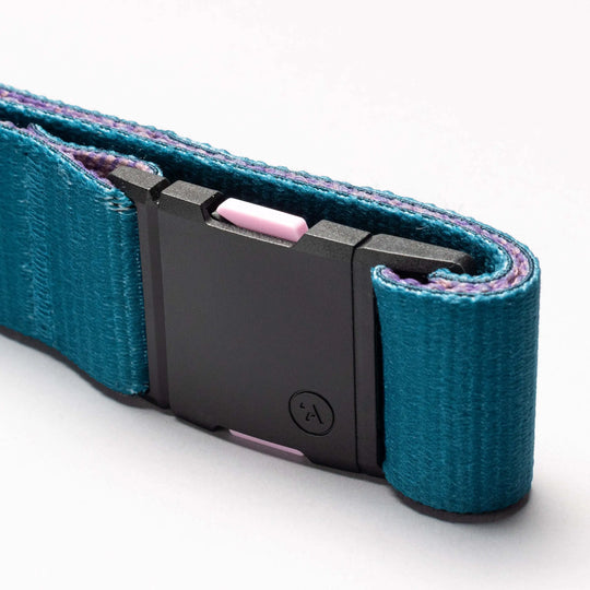 A close-up of the Arcade Belts National Geographic teal belt, featuring a black rectangular plastic buckle and a small pink accent, coiled on a plain white background—built for new adventures.