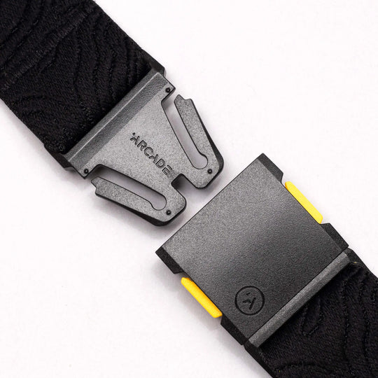 Close-up of the National Geographic by Arcade Belts buckle with a secure, interlocking design and subtle yellow accents on a white background—ideal for those wanting a modern Low Profile Belt.