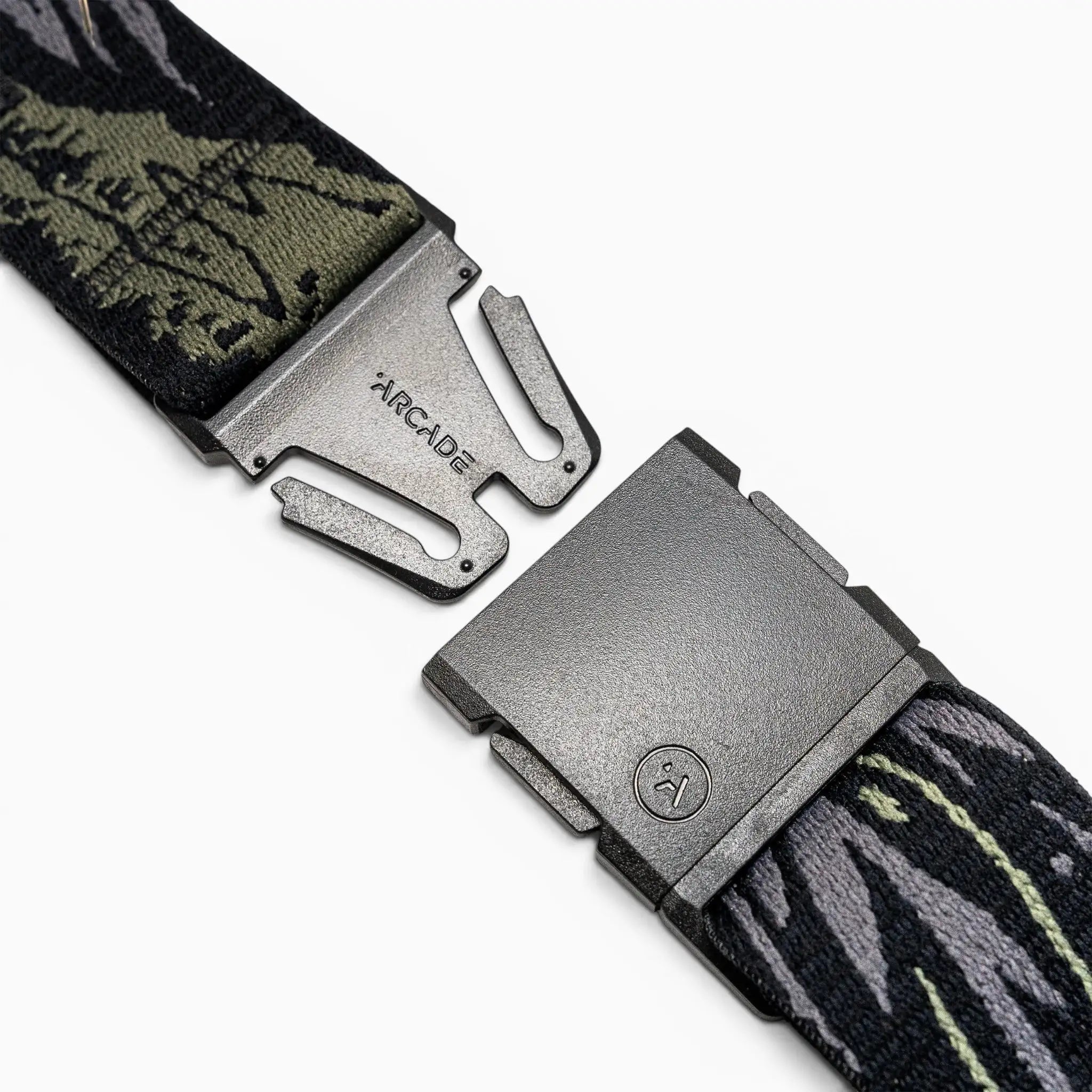A close-up of the Arcade Belts Out of Range, featuring a metal buckle with visible branding, partially unclasped to reveal patterned green and black fabric.