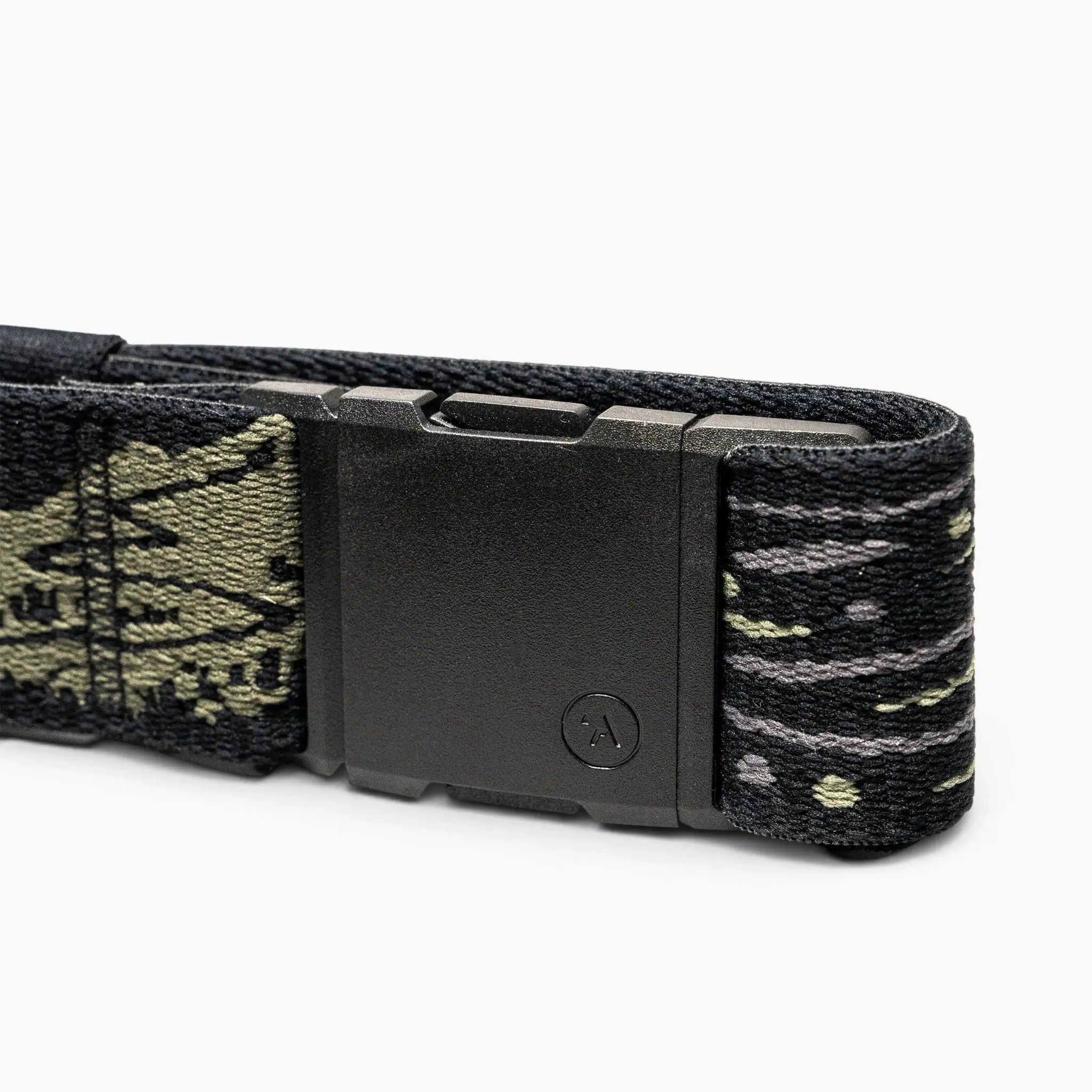 A close-up of the Arcade Belts Out of Range belt shows a black rectangular buckle and stretch webbing with a green and gray camo pattern. A small circular A logo decorates the buckle, ensuring both comfort and branded style.