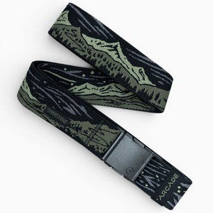The Out of Range belt by Arcade Belts is black and olive green with a mountain landscape design, a black rectangular buckle, and “ARCADE” printed near the end of the elastic stretch fabric.