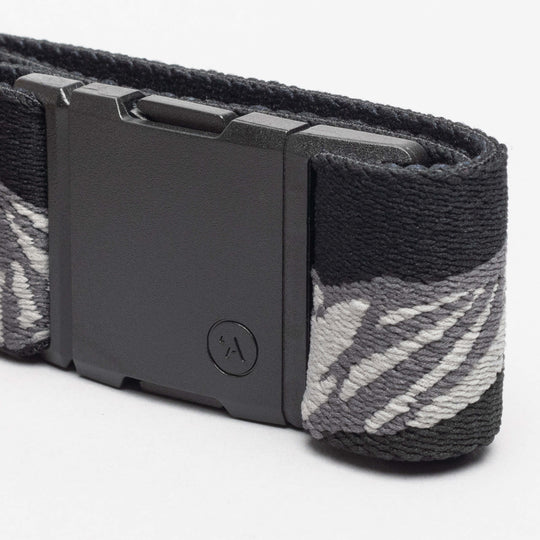 A close-up of the Arcade Belts POW x Joseph Toney, a low profile belt with a matte black rectangular plastic buckle, featuring a subtle textured pattern, small circular logo, and elastic gray and white abstract design.