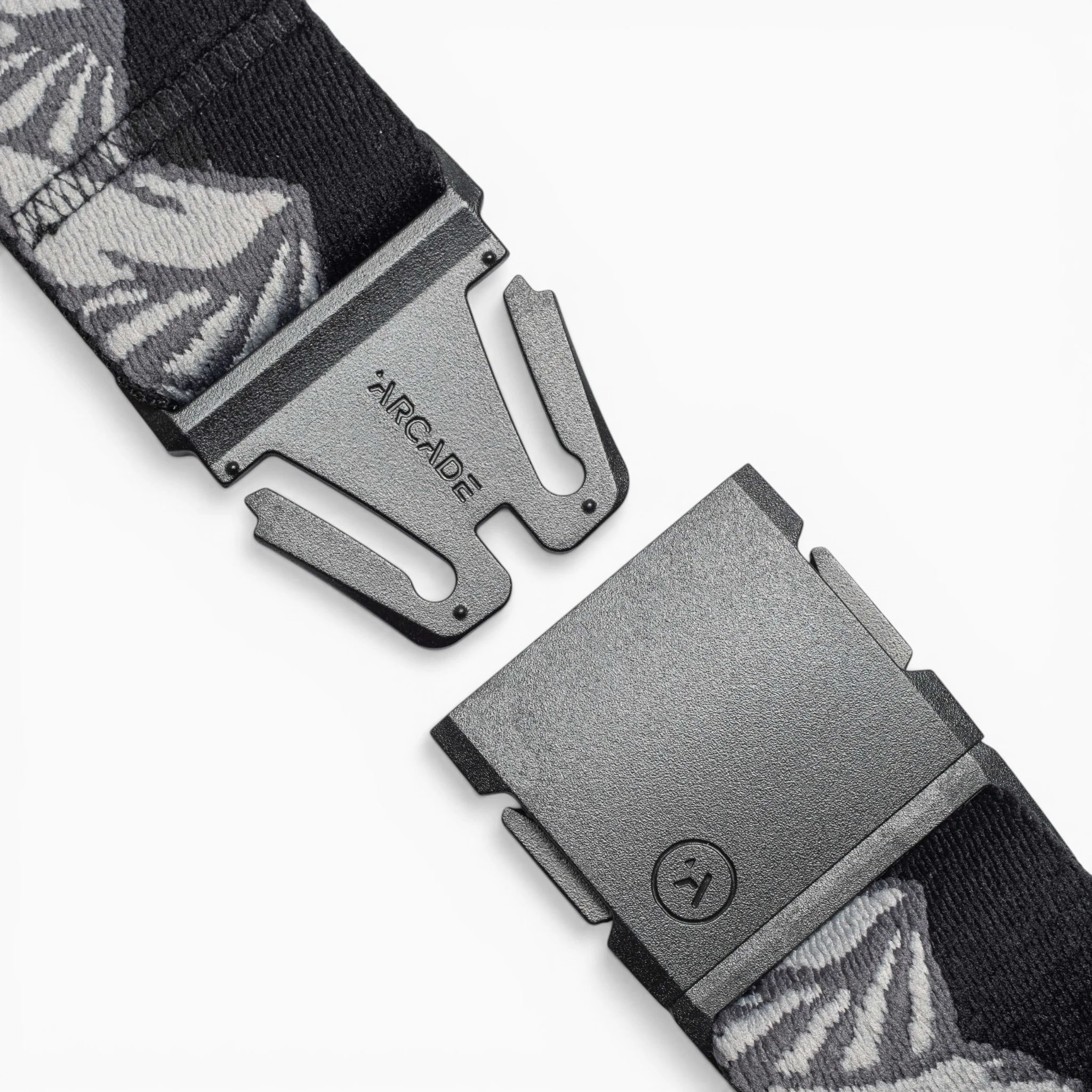 A close-up of the Arcade Belts POW x Joseph Toney, a black belt with gray and white patterns, features an open black buckle and ARCADE branding, showcasing its low-profile design.