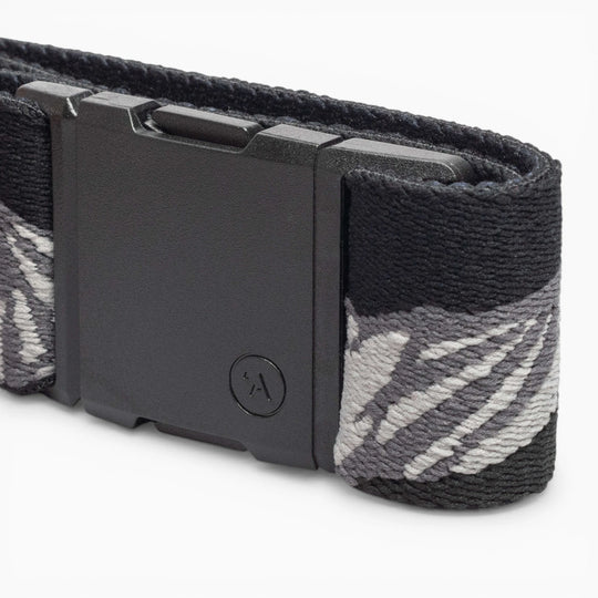 A close-up of the Arcade Belts POW x Joseph Toney, a low profile belt with a matte black rectangular plastic buckle, featuring a subtle textured pattern, small circular logo, and elastic gray and white abstract design.