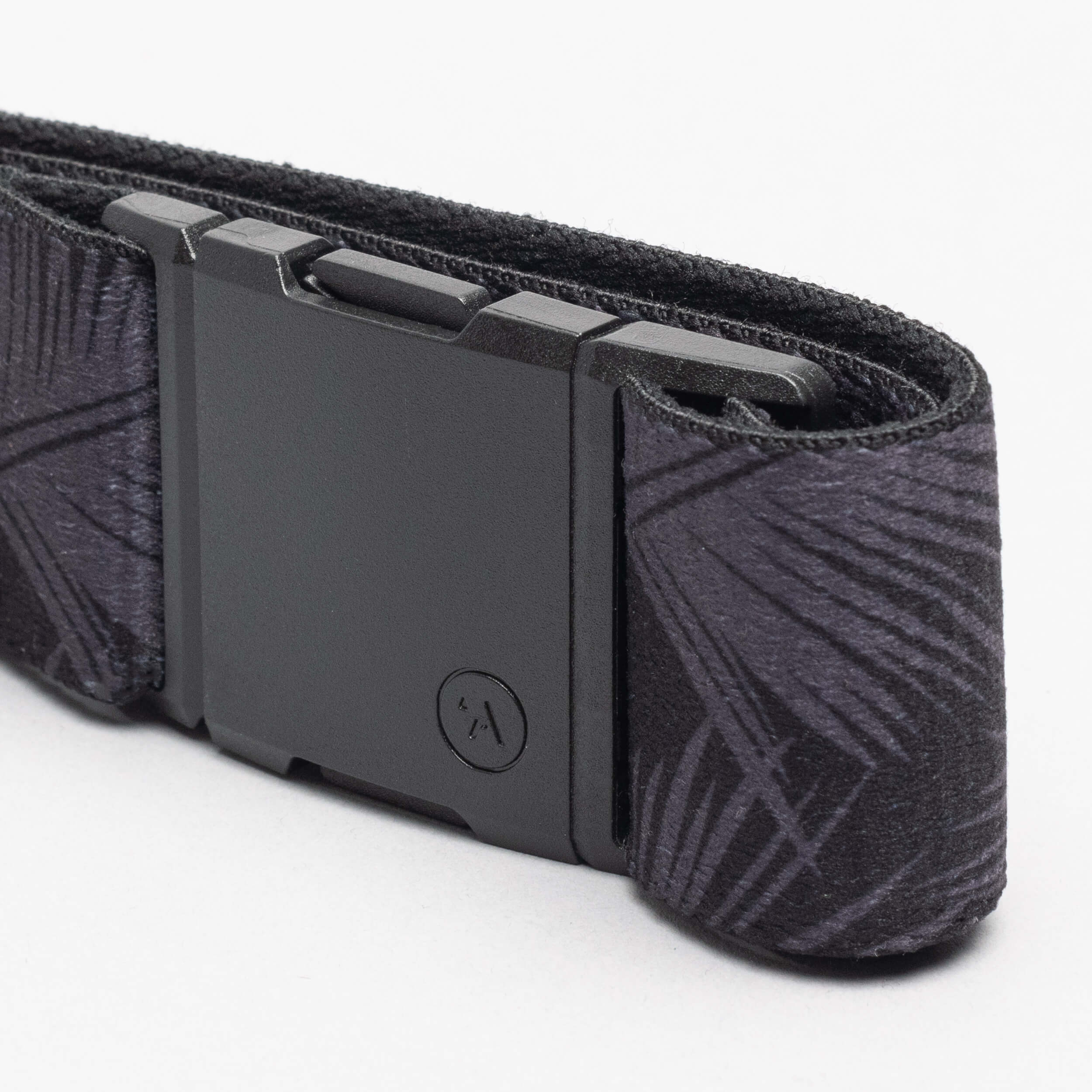 A close-up of the Arcade Belts Island Collection: a black fabric belt with a geometric Hawaiian-inspired pattern and a matte black rectangular buckle, coiled on a plain white background.