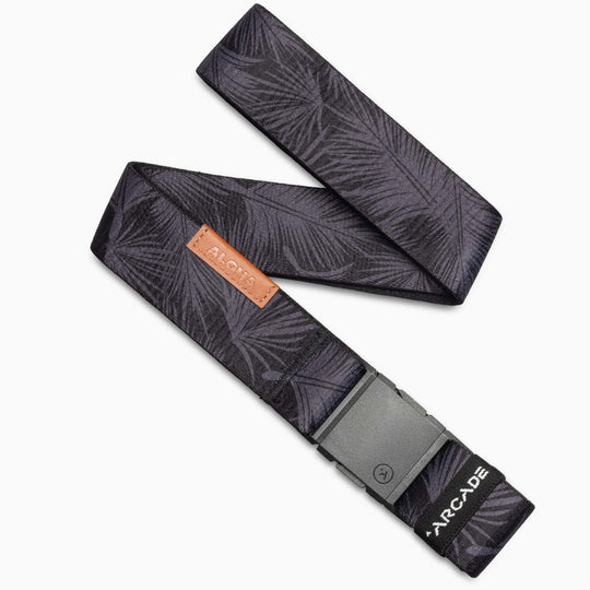 A folded black Arcade Belts Island Collection belt with a dark gray palm leaf pattern, gray buckle, brown leather Arcade tag, and a white logo at the end.