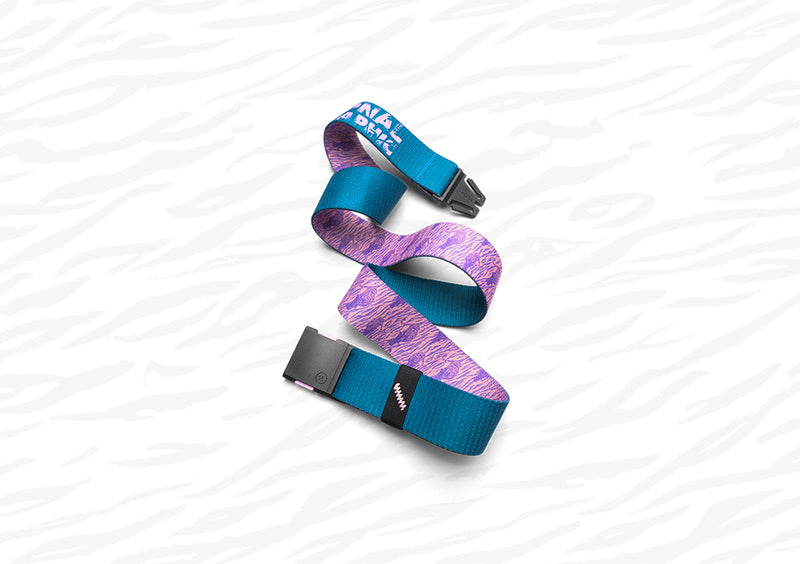 A colorful belt with a blue, purple, and white abstract pattern, featuring a black buckle, is laid out in a loose zigzag shape on a white background with subtle wavy gray lines.