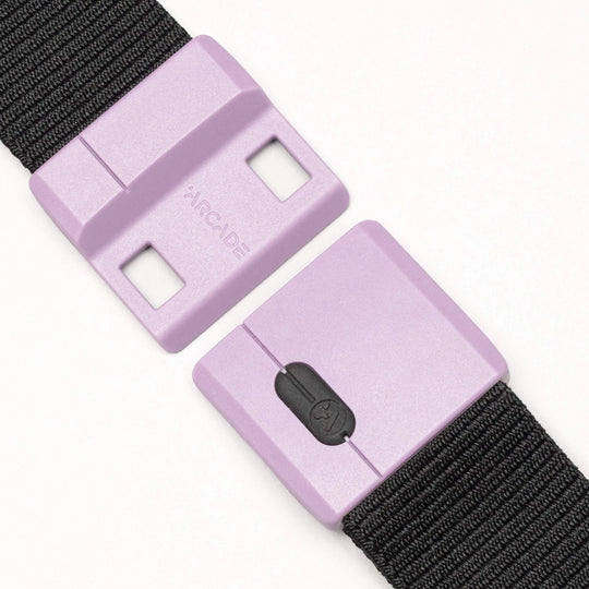 A close-up of the Arcade Belts Polar, a black woven belt with a durable lavender plastic buckle, partially open and embossed with the brand name.