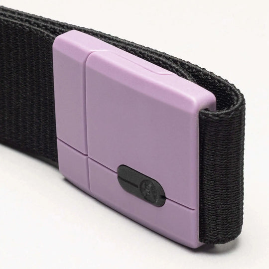 A close-up of the Arcade Belts Polar Mag: a black fabric belt with a rectangular light purple plastic buckle and small black sliding tension lock, shown against a plain, light background.