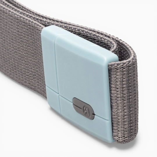 A close-up of the Polar Mag by Arcade Belts shows a gray woven fabric strap paired with a rectangular, light blue plastic buckle featuring SwiftLock technology—a durable design with a small switch for secure and reliable fastening.