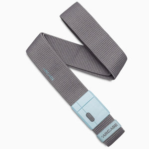A Charcoal/Cove fabric belt from Arcade Belts, the Polar Mag, is shown laid out in an S-shape. It features a light blue plastic buckle with SwiftLock technology for a secure magnetic closure, and both the belt and buckle display the word "ARCADE.
