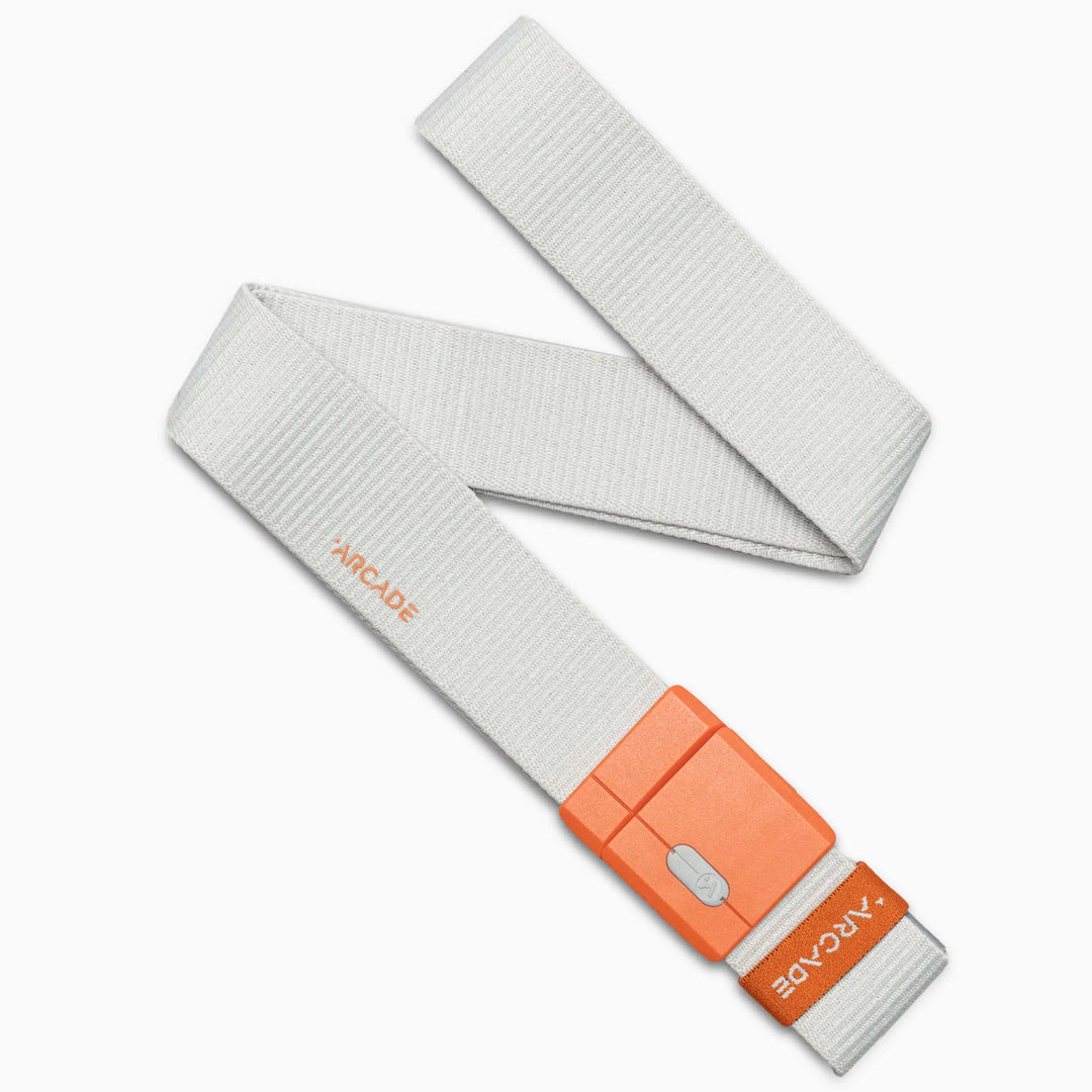 The Arcade Belts Polar Mag belt in Glacial Flame features light gray fabric and an orange rectangular buckle with "ARCADE" in white text. Partially coiled, it rests on a white background.