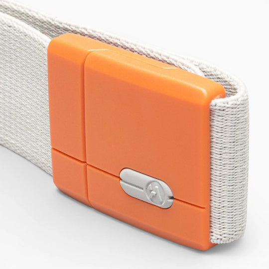 A close-up of the Polar Mag by Arcade Belts, showcasing a white fabric strap with an orange plastic buckle that features SwiftLock technology and a small silver screw in the center for added security.