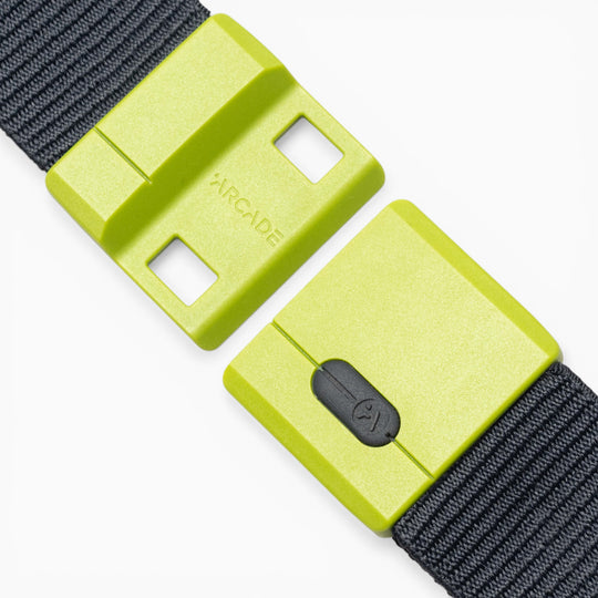 A close-up of the Arcade Belts Polar Mag, featuring a neon green rectangular buckle with black straps. This durable belt displays the word “ARCADE” and includes a small black clasp, enhanced by SwiftLock technology for quick and reliable fastening.