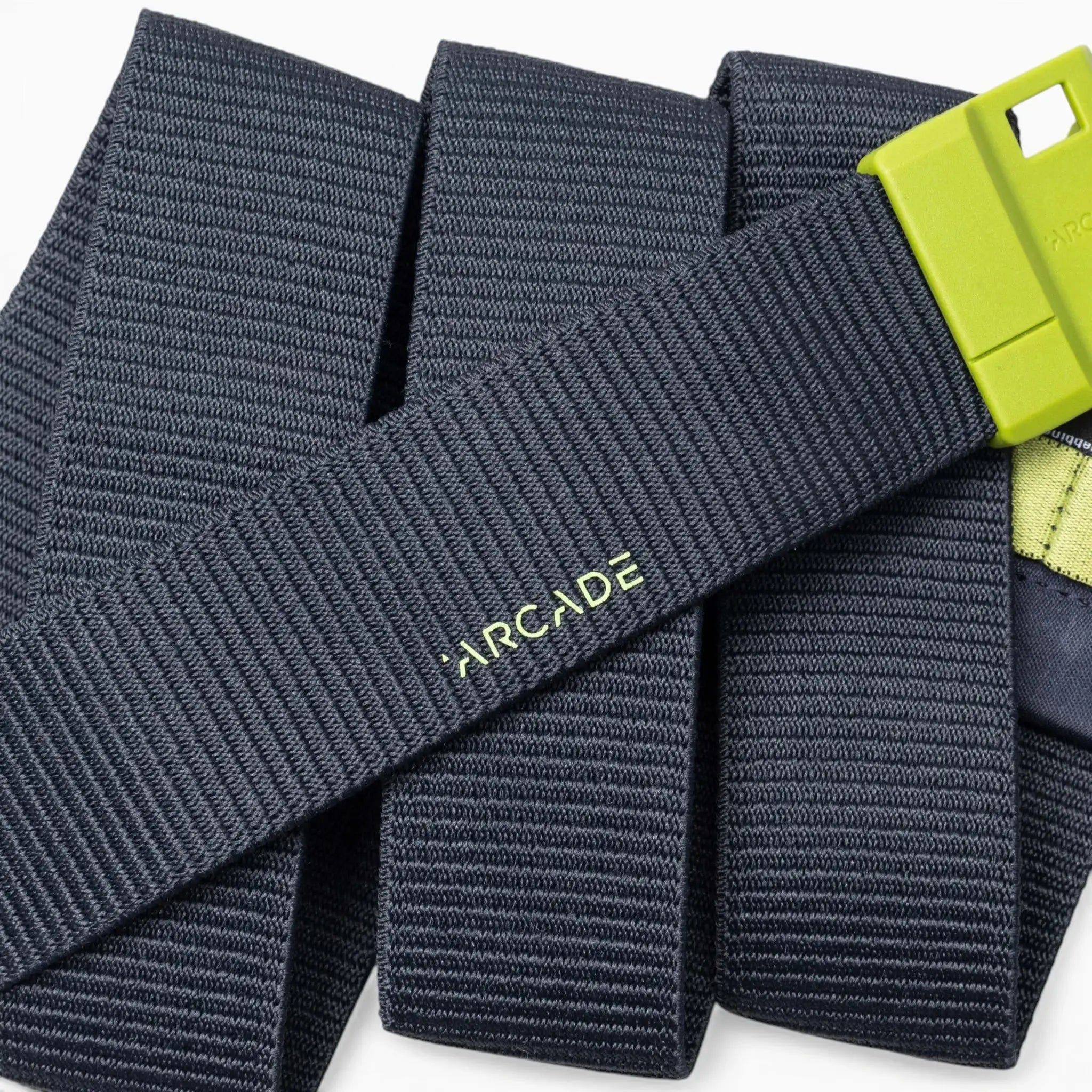 A close-up of a dark gray Arcade Belts Polar Mag durable belt with a lime green buckle, featuring SwiftLock technology, laid out in overlapping folds.