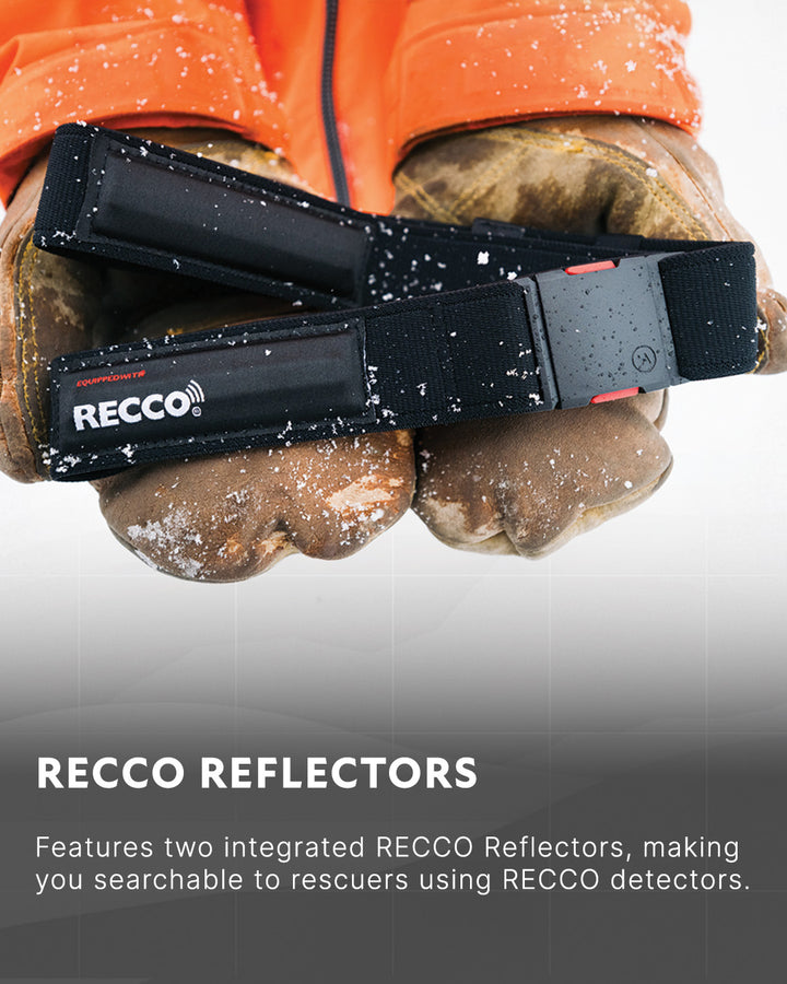A person wearing orange sleeves and brown gloves holds two black RECCO reflectors with visible branding. Snow specks are scattered on the gloves and reflectors. Text below describes the RECCO reflectors’ purpose.