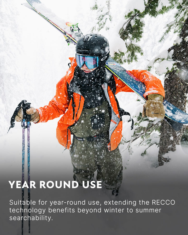 A skier wearing an orange jacket and helmet carries skis on their shoulder while standing in a snowy forest. Text reads: “YEAR ROUND USE. Suitable for year-round use, extending RECCO technology benefits beyond winter to summer searchability.”.