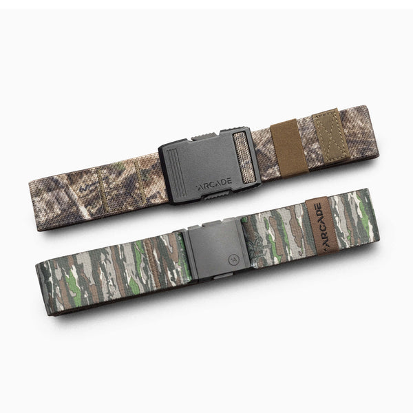 Two camouflage-patterned fabric belts from Arcade Belts' Realtree Kit are displayed side by side on a white background. Perfect for your camo kit, the top belt showcases Realtree-inspired brown and tan tones, while the bottom belt highlights performance essentials in green and gray shades.