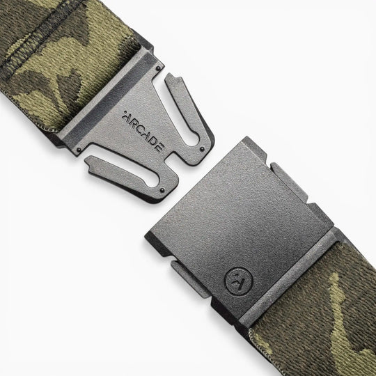 Close-up of the Roark x Arcade adventure belt by Arcade Belts, showcasing its camouflage pattern and matte black quick-release buckle, partially unfastened on a white background. Performance stretch offers comfort for any journey.