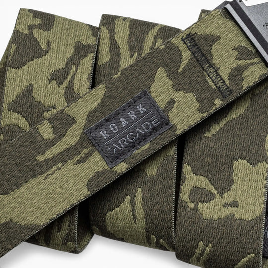 A close-up of green and black camouflage-patterned Roark x Arcade belts by Arcade Belts, featuring a black stitched patch with the ROARK ARCADE logo on one belt.