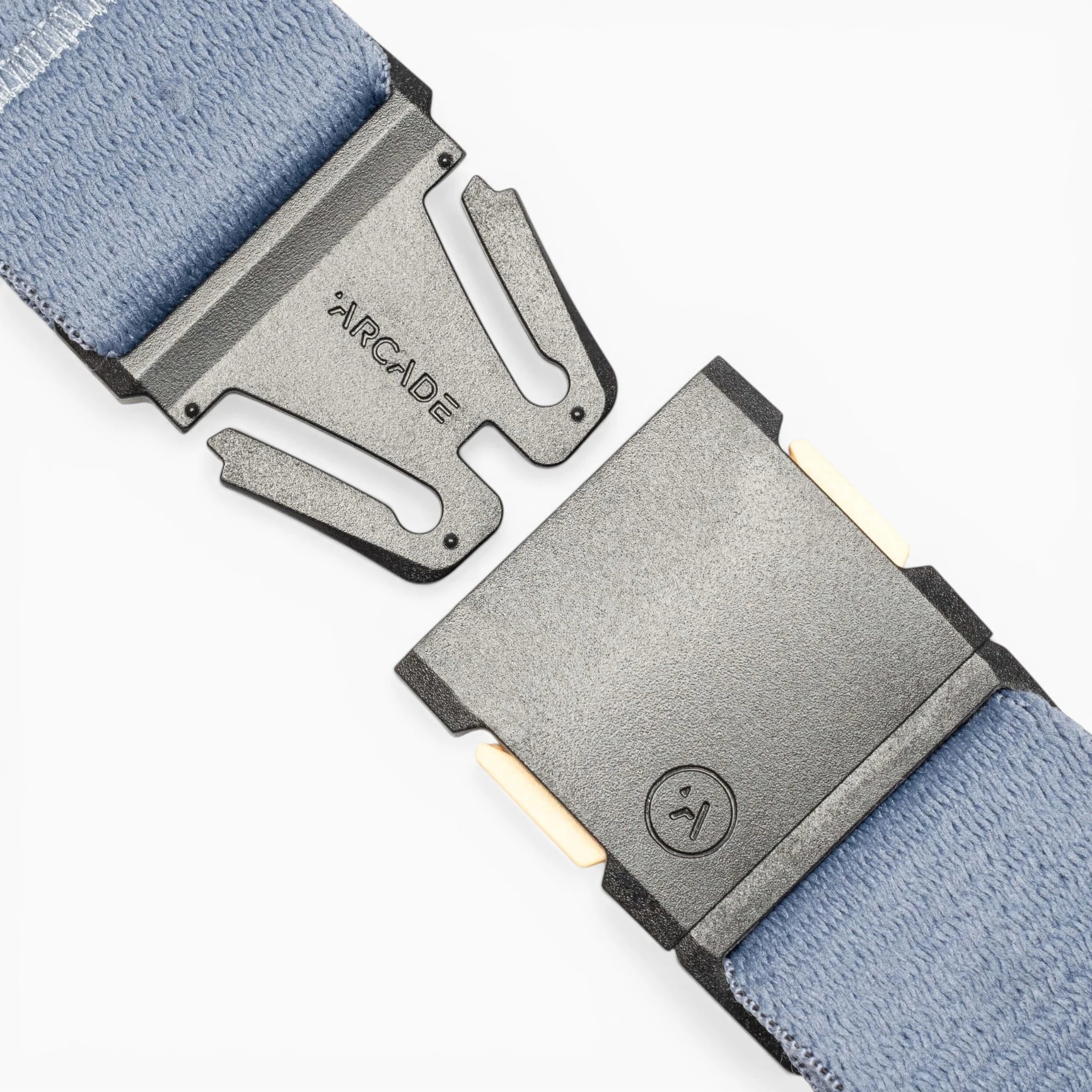 Close-up of a metal buckle on a light blue Save the Waves surf belt by Arcade Belts; one side shows the brand name, and the other features a smiley face logo, supporting conservation and Save the Waves initiatives.